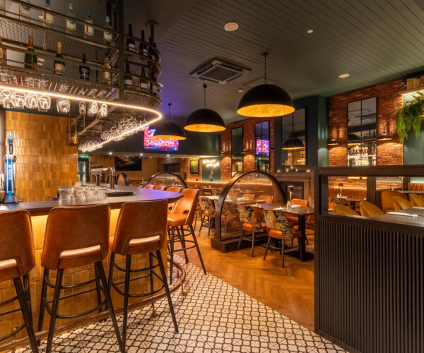 Bar area with curved timber panelling, brass footrail and pendant lighting